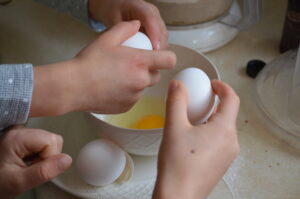 Cooking with Children- Two kids crack eggs