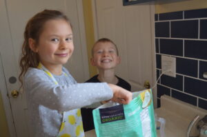 Cooking with Children- Two kids measure coconut flour
